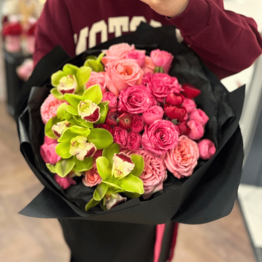 bukiet róż różowych i gałązkowych, storczyk cymbidium zielony, czarny papier