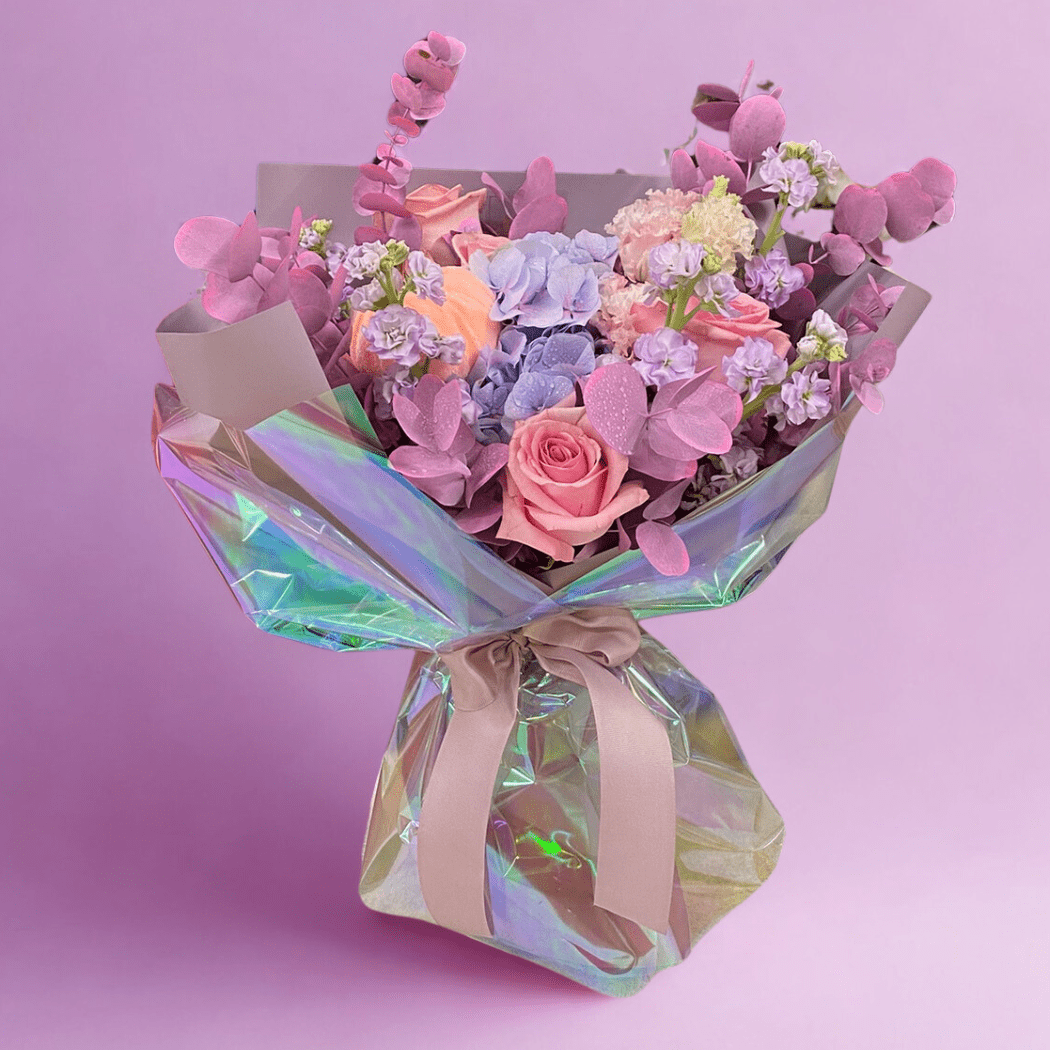 Bukiet z różowych i fioletowych kwiatów w błyszczącej folii opalizującej