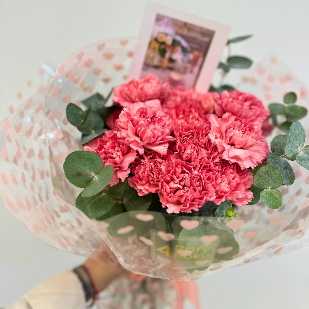 bukiet goździków w papierze ozdobnym i eukaliptusem